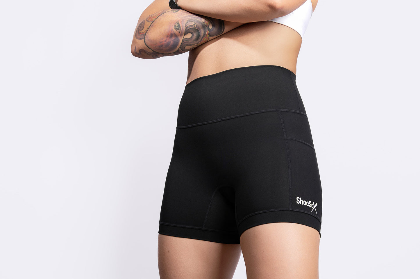 Person wearing black athletic shorts with a visible brand logo on a white background
